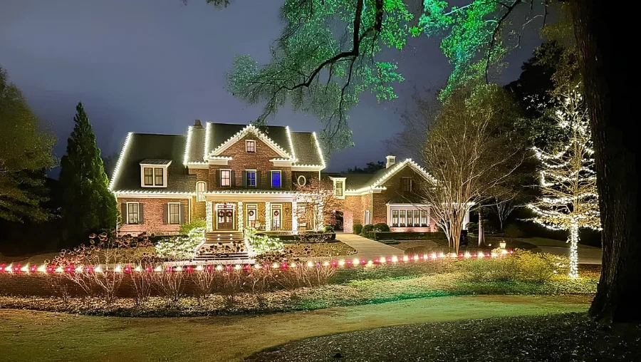 Brick colonial home with pink and white Christmas roofline lighting