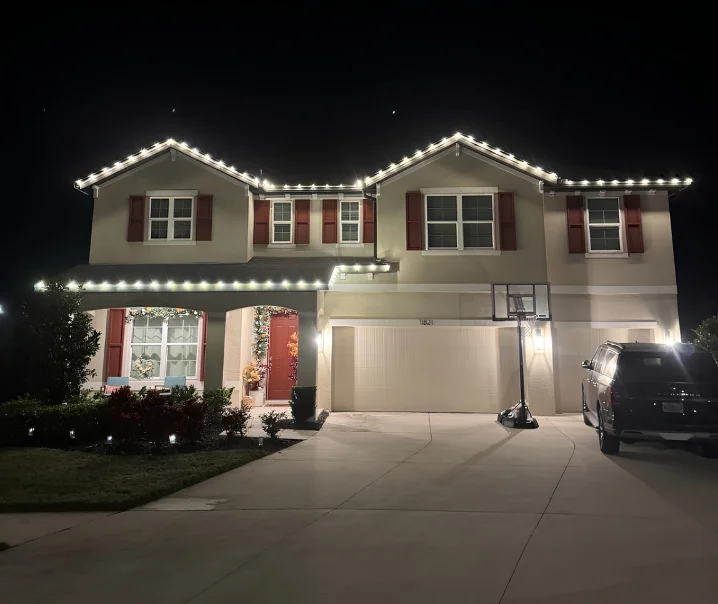 Two-story home with warm white roofline Christmas lighting