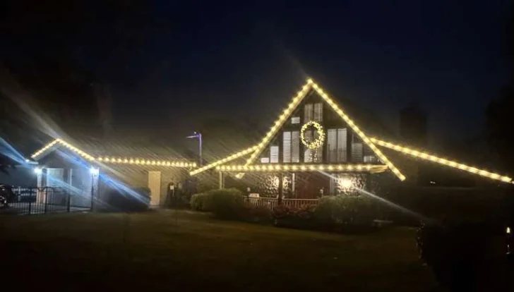 A-frame home in Brandon, FL with warm white roofline outline lighting and a lit wreath
