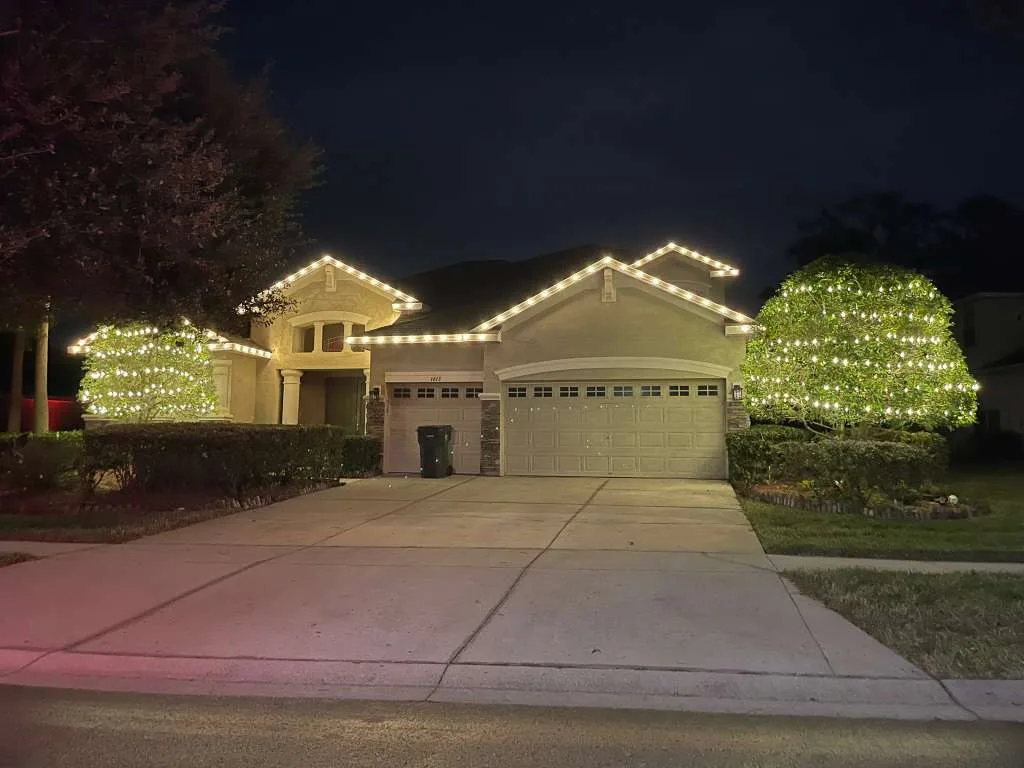 Estate home in Brandon, FL with warm white roofline Christmas lighting and lit shrubs