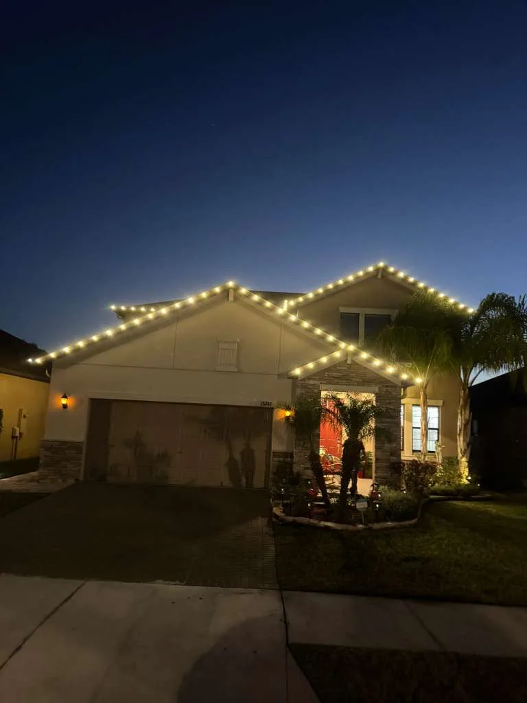 Home in Riverview, FL at dusk with warm white roofline Christmas lighting and palm trees